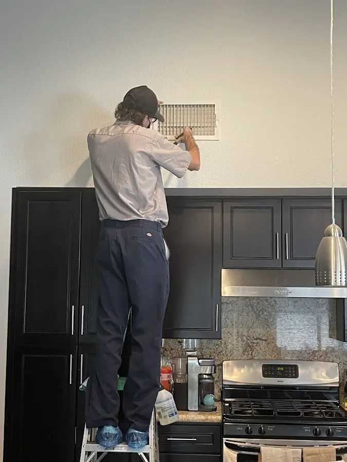 Technician inspecting an air vent during HVAC service in Haysville